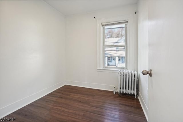 spare room featuring dark wood-type flooring and radiator