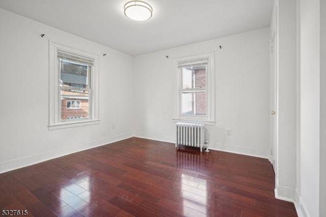 spare room featuring radiator heating unit and dark wood-type flooring