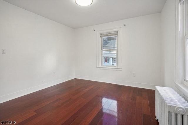 empty room featuring radiator heating unit and dark hardwood / wood-style floors