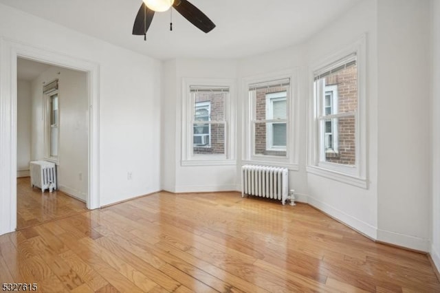 empty room featuring a wealth of natural light, light wood-type flooring, and radiator