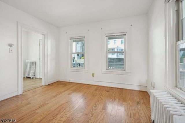 empty room with radiator heating unit and light wood-type flooring