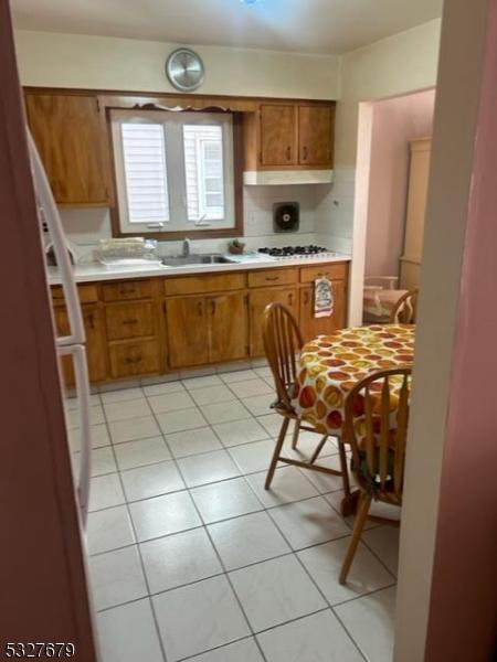 kitchen featuring light tile patterned flooring, white gas stovetop, and sink