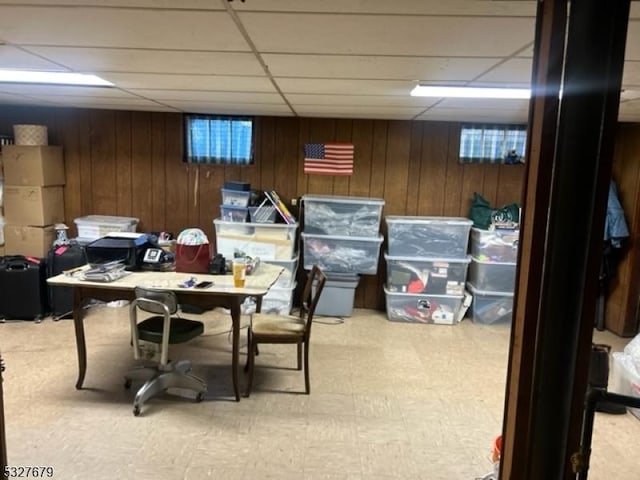 office space with a drop ceiling and wood walls