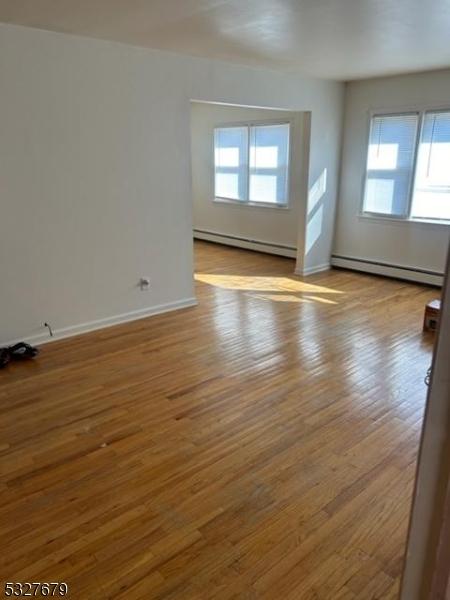 spare room featuring light hardwood / wood-style floors, a wealth of natural light, and a baseboard heating unit