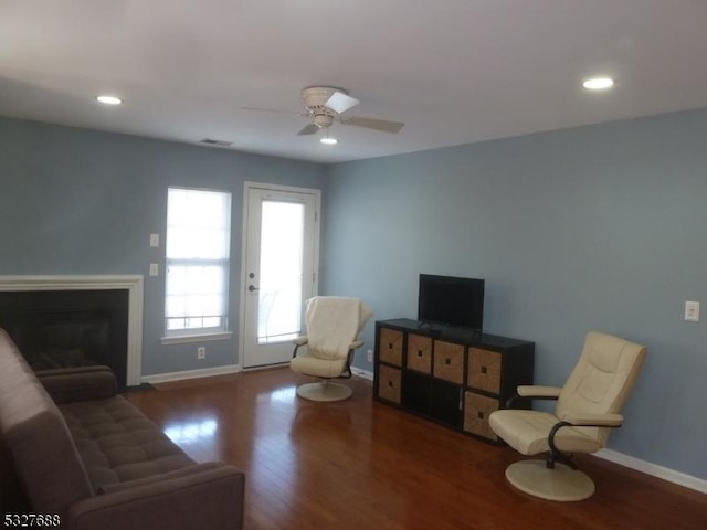 living room featuring ceiling fan and dark wood-type flooring