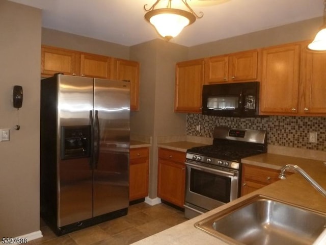 kitchen featuring appliances with stainless steel finishes, tasteful backsplash, light tile patterned floors, and sink