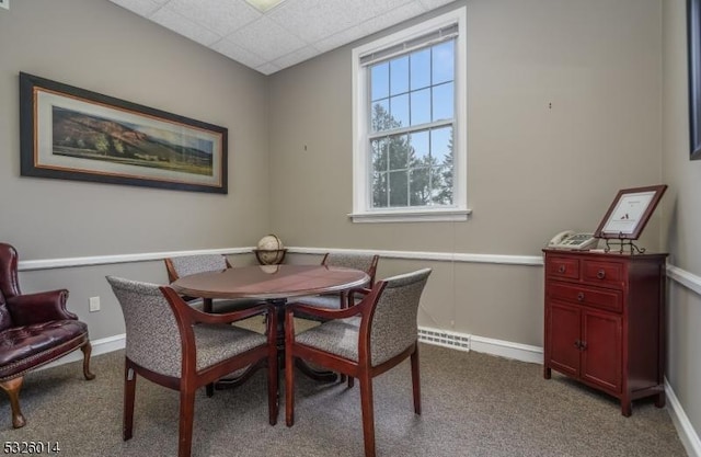 carpeted dining area featuring a drop ceiling