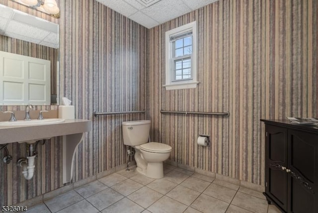 bathroom featuring tile patterned flooring, a drop ceiling, and toilet