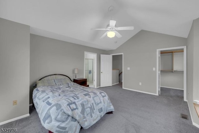 carpeted bedroom featuring a walk in closet, a closet, vaulted ceiling, and ceiling fan