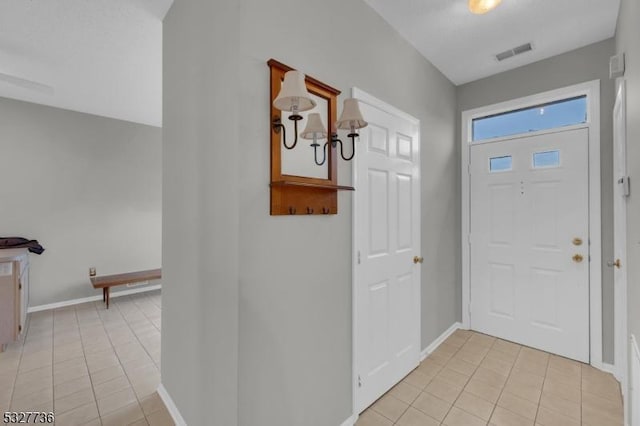 tiled entryway featuring a notable chandelier