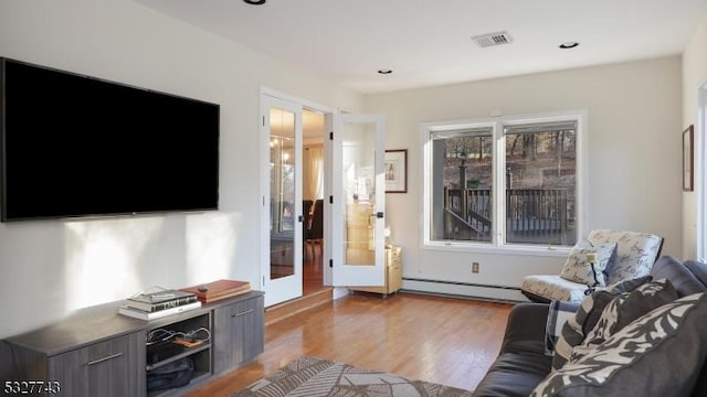 living room with french doors, a baseboard heating unit, and light hardwood / wood-style flooring