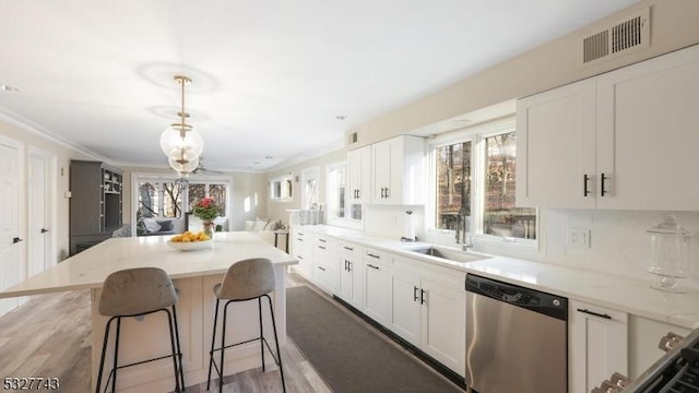 kitchen with sink, white cabinets, stainless steel dishwasher, a kitchen island, and plenty of natural light