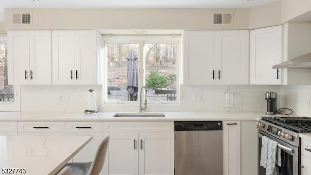 kitchen featuring stainless steel appliances, sink, white cabinetry, decorative backsplash, and light stone countertops