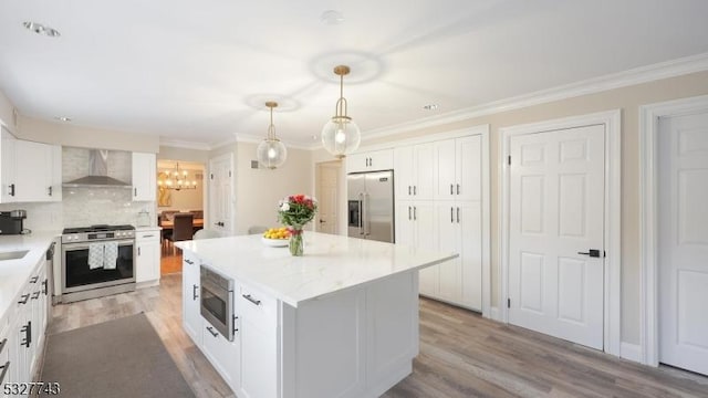 kitchen featuring a kitchen island, wall chimney range hood, white cabinetry, and appliances with stainless steel finishes