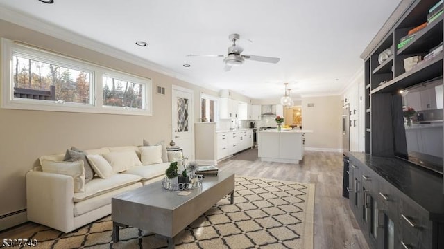 living room featuring ornamental molding, light wood-type flooring, ceiling fan, and a baseboard radiator