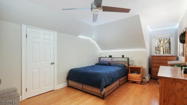 bedroom featuring vaulted ceiling, a baseboard heating unit, light wood-type flooring, and ceiling fan