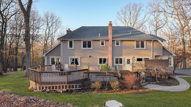 back of house featuring a lawn and a wooden deck