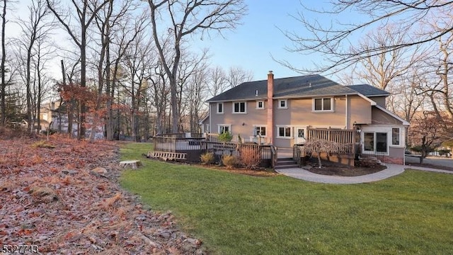 rear view of house with a deck and a lawn