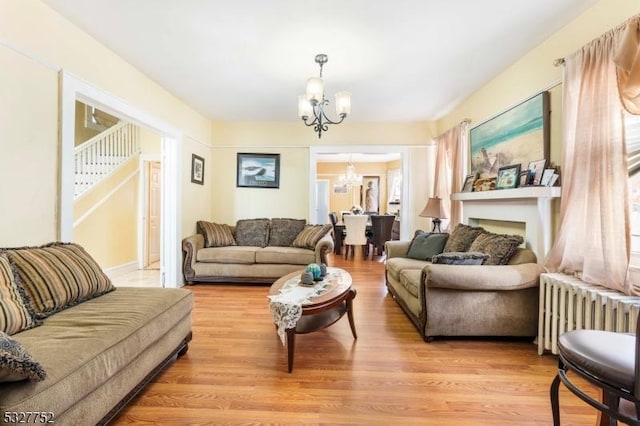 living room featuring light hardwood / wood-style floors, radiator heating unit, and an inviting chandelier