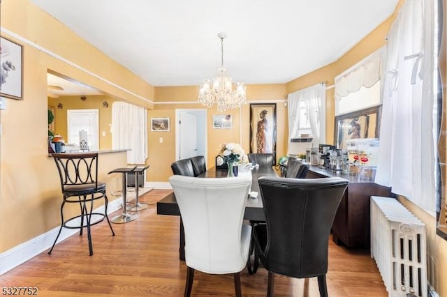 dining area featuring a notable chandelier, light wood-type flooring, and radiator