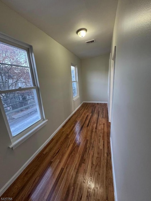 spare room featuring plenty of natural light and dark hardwood / wood-style flooring