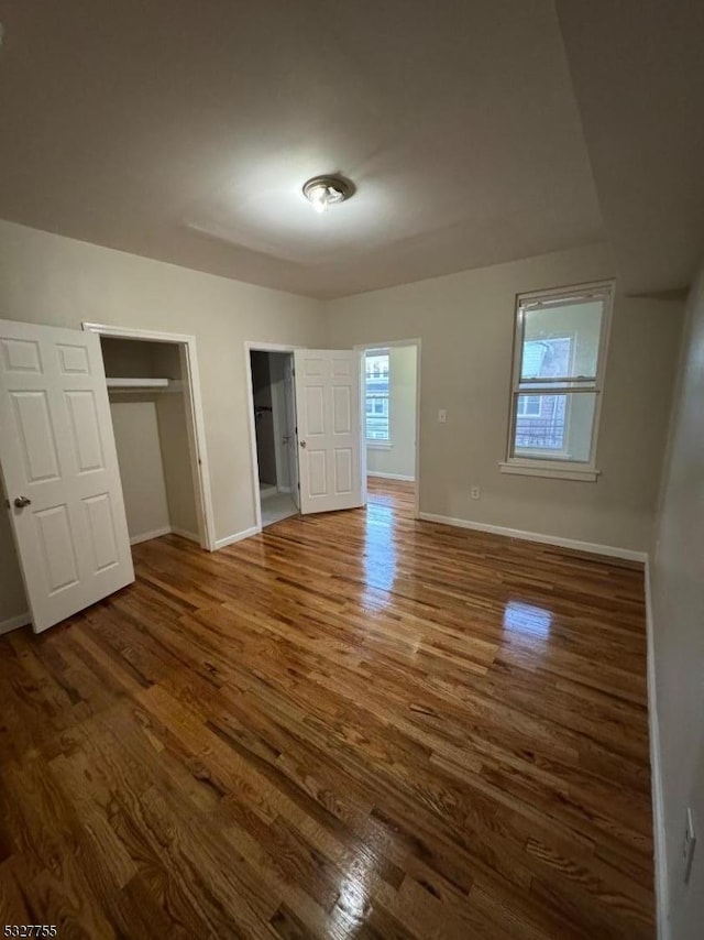 unfurnished bedroom featuring a closet and dark hardwood / wood-style flooring