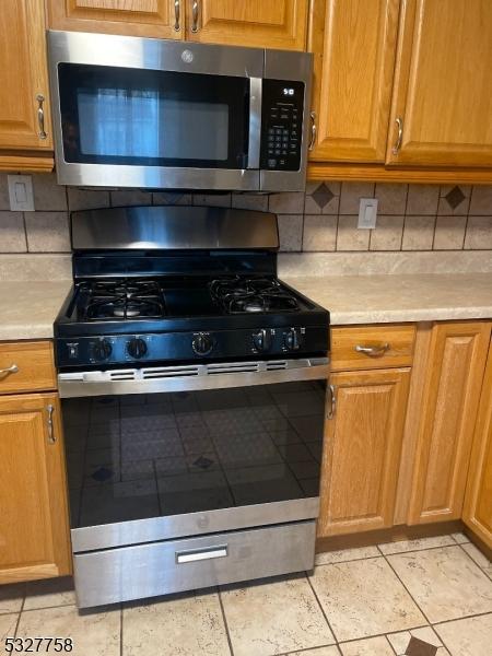 kitchen featuring decorative backsplash, appliances with stainless steel finishes, and light tile patterned floors