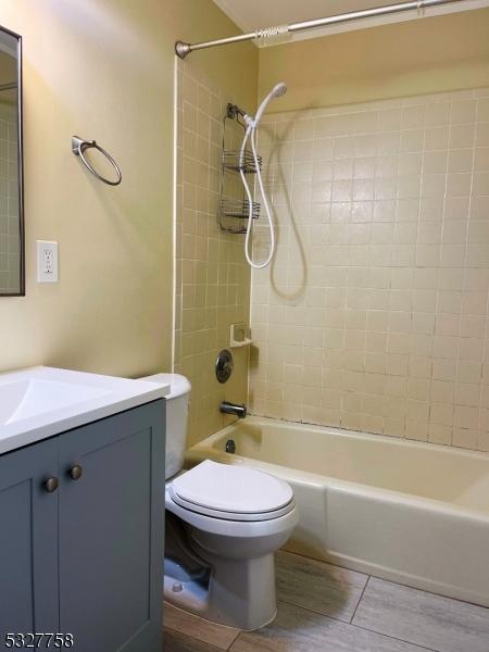 full bathroom with hardwood / wood-style floors, vanity, toilet, and tiled shower / bath combo