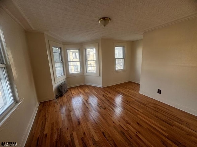 unfurnished room featuring radiator heating unit and wood-type flooring