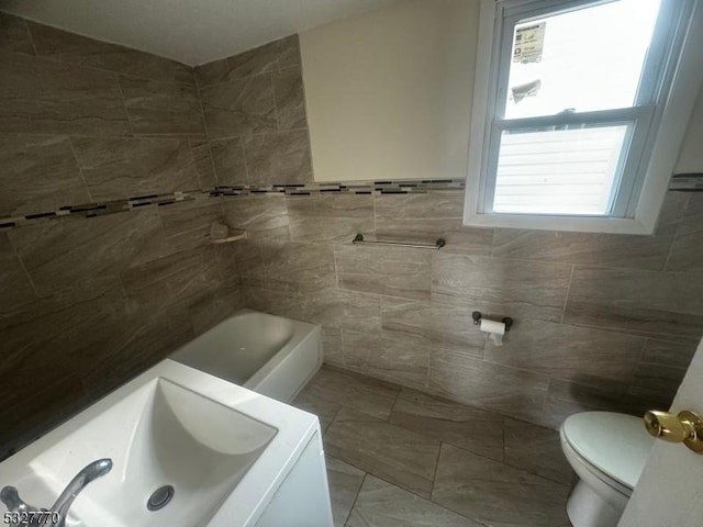 bathroom featuring sink, plenty of natural light, toilet, and tile walls