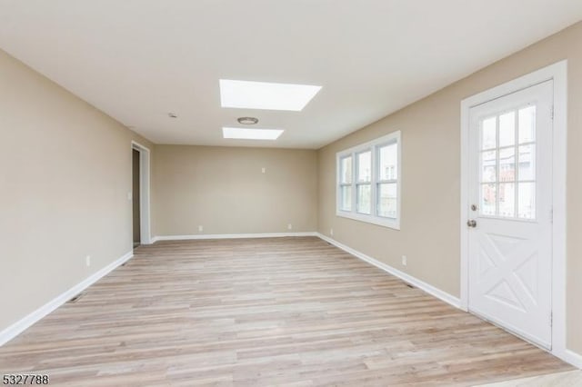 interior space featuring light wood-type flooring and a skylight