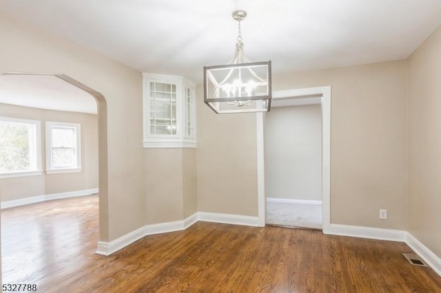 unfurnished dining area with dark hardwood / wood-style flooring and an inviting chandelier