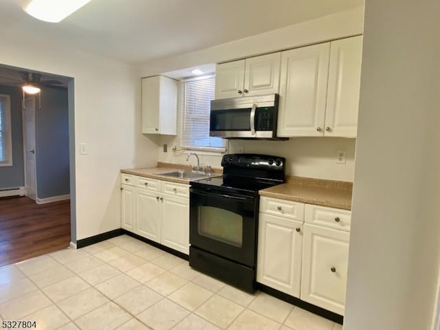 kitchen with sink, light tile patterned floors, black electric range, a baseboard heating unit, and white cabinets