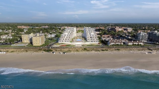 birds eye view of property with a water view and a beach view