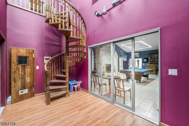 stairway featuring billiards, a towering ceiling, and hardwood / wood-style flooring