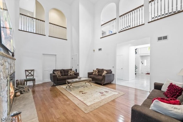 living room featuring a fireplace, hardwood / wood-style floors, and a towering ceiling