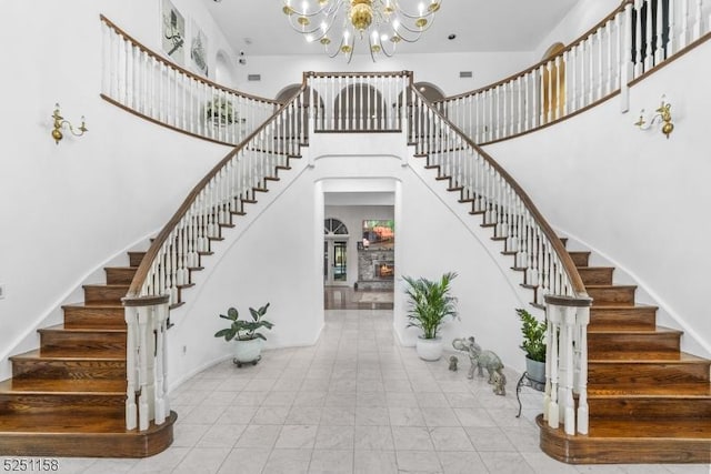 stairs featuring a towering ceiling, a fireplace, and an inviting chandelier