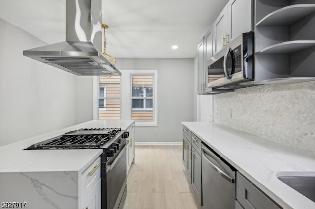 kitchen featuring light wood-type flooring, light stone counters, gray cabinetry, stainless steel appliances, and extractor fan