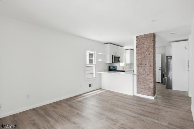 unfurnished living room featuring hardwood / wood-style floors, decorative columns, and sink