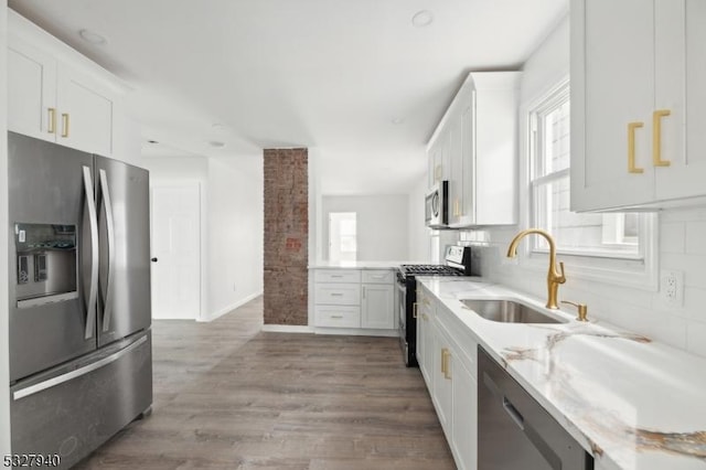 kitchen featuring white cabinetry, sink, tasteful backsplash, wood-type flooring, and appliances with stainless steel finishes