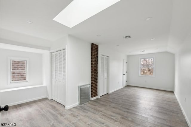 bonus room with light wood-type flooring and a skylight