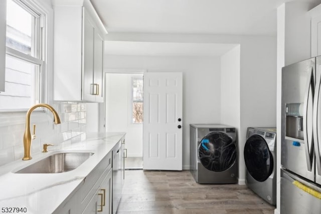 laundry area featuring separate washer and dryer, sink, and light hardwood / wood-style floors