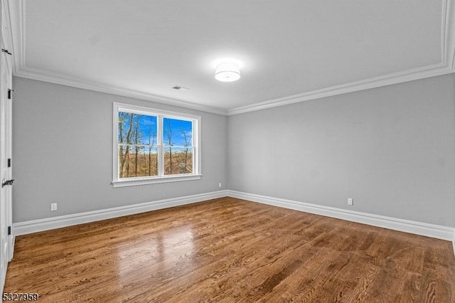 spare room featuring hardwood / wood-style floors and crown molding