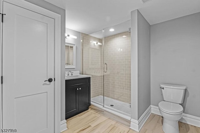 bathroom with wood-type flooring, vanity, toilet, and a shower with shower door