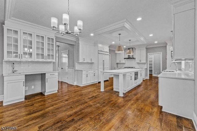 kitchen featuring a center island, paneled fridge, dark hardwood / wood-style floors, pendant lighting, and white cabinets