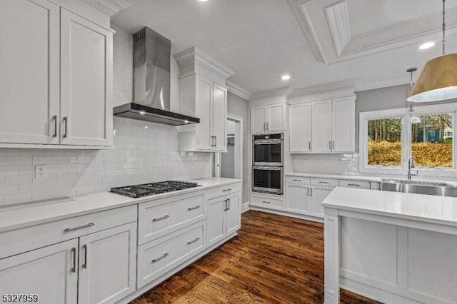 kitchen with wall chimney range hood, crown molding, dark hardwood / wood-style flooring, white cabinetry, and stainless steel appliances