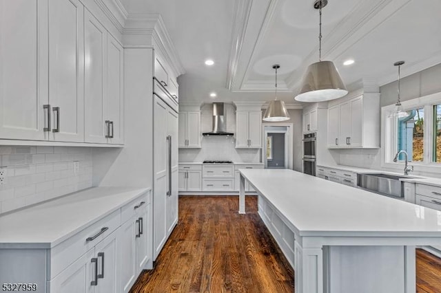 kitchen featuring pendant lighting, wall chimney exhaust hood, dark hardwood / wood-style flooring, and white cabinets