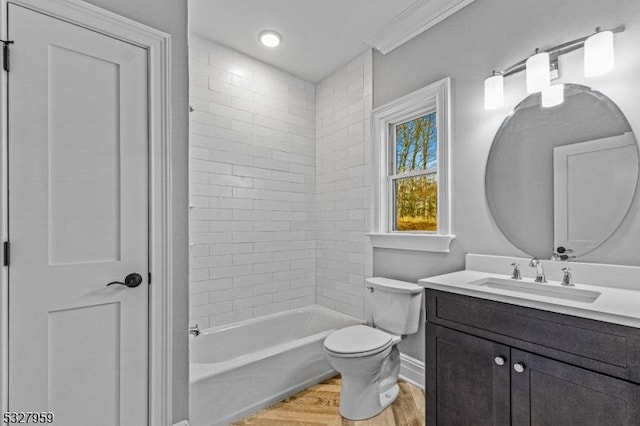 full bathroom with hardwood / wood-style floors, vanity, tiled shower / bath, crown molding, and toilet