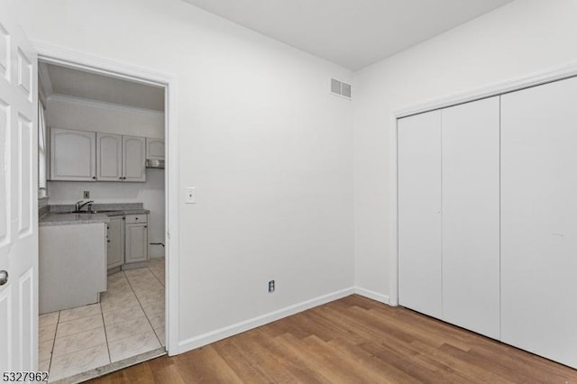 unfurnished bedroom with light wood-type flooring, sink, and a closet