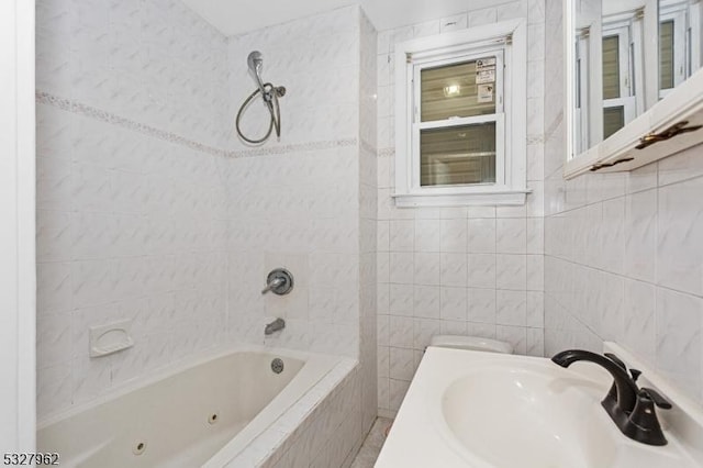 bathroom with tiled shower / bath, tile walls, and sink